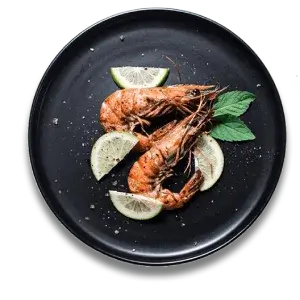 Grilled prawns with lime slices on a black plate.