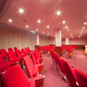 Empty auditorium with red seats and pink lighting.