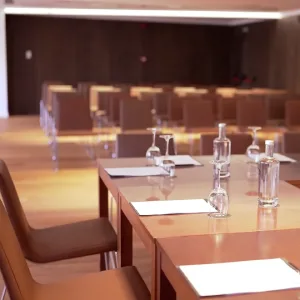 Empty conference room with tables, chairs, notebooks, and water bottles.