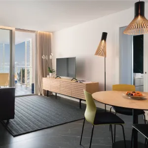 Modern living room with TV, dining table, chairs, and balcony view.