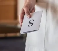 Hand holding a card with the letter "S."