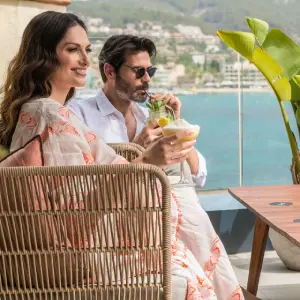 Couple relaxing with drinks on a terrace overlooking the ocean.