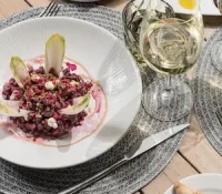 Beet risotto with endive and wine on a table setting.