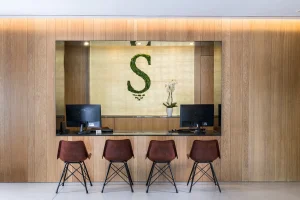 Four chairs and computers at a wooden reception desk with an "S" on the back wall.