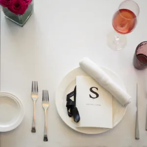 Elegant table setting with a menu, napkin, and wine glass on a white tablecloth.