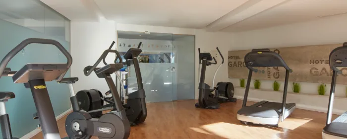 Fitness room with treadmills and exercise bikes on a wooden floor, bright lighting.