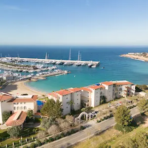 Aerial view of a coastal town with a marina and buildings near the sea.