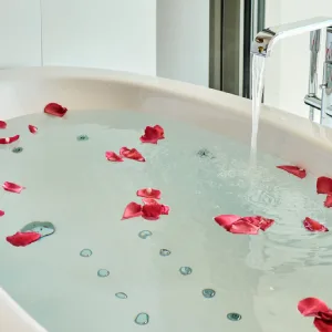 Bathtub with rose petals and running water.