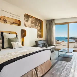 Modern hotel room with a sea view, stylish decor, bed, and sofa.