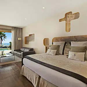 Luxurious room with a large bed, sofa, and sea view balcony.