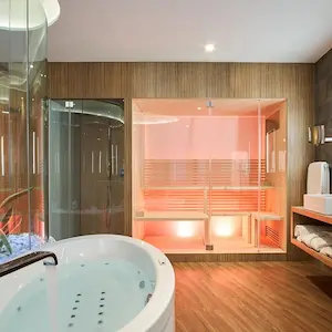 Luxurious bathroom with a jacuzzi, glass shower, and infrared sauna on wood flooring.