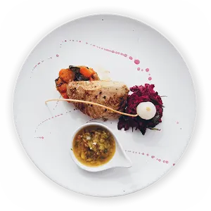 Gourmet dish with chicken, sauce, and vegetables on a white plate with artistic garnish.