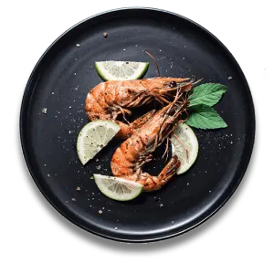 Grilled shrimp with lime slices and mint on a black plate.