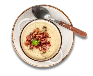 Creamy soup with bacon and parsley in a bowl, served with a spoon on a plate.
