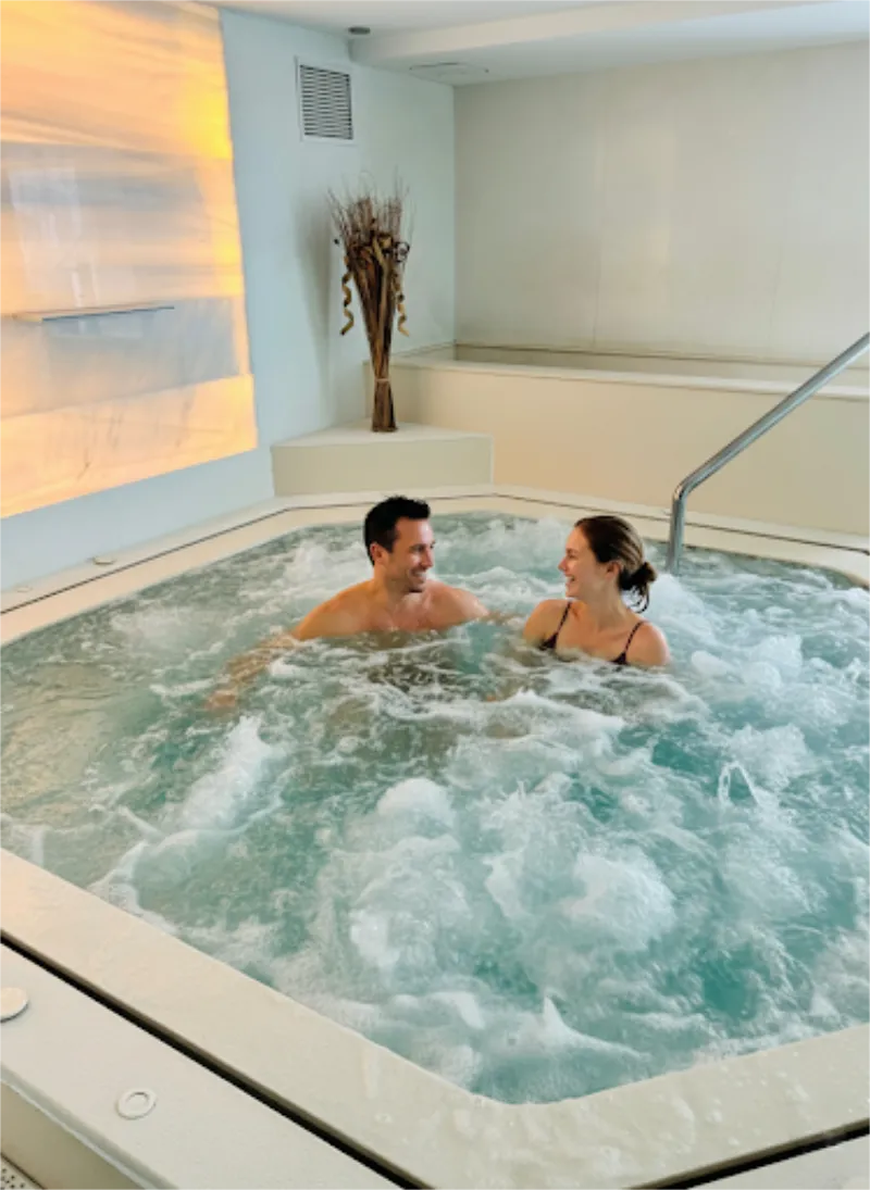 Pareja sonriendo en una ba&ntilde;era de hidromasaje.