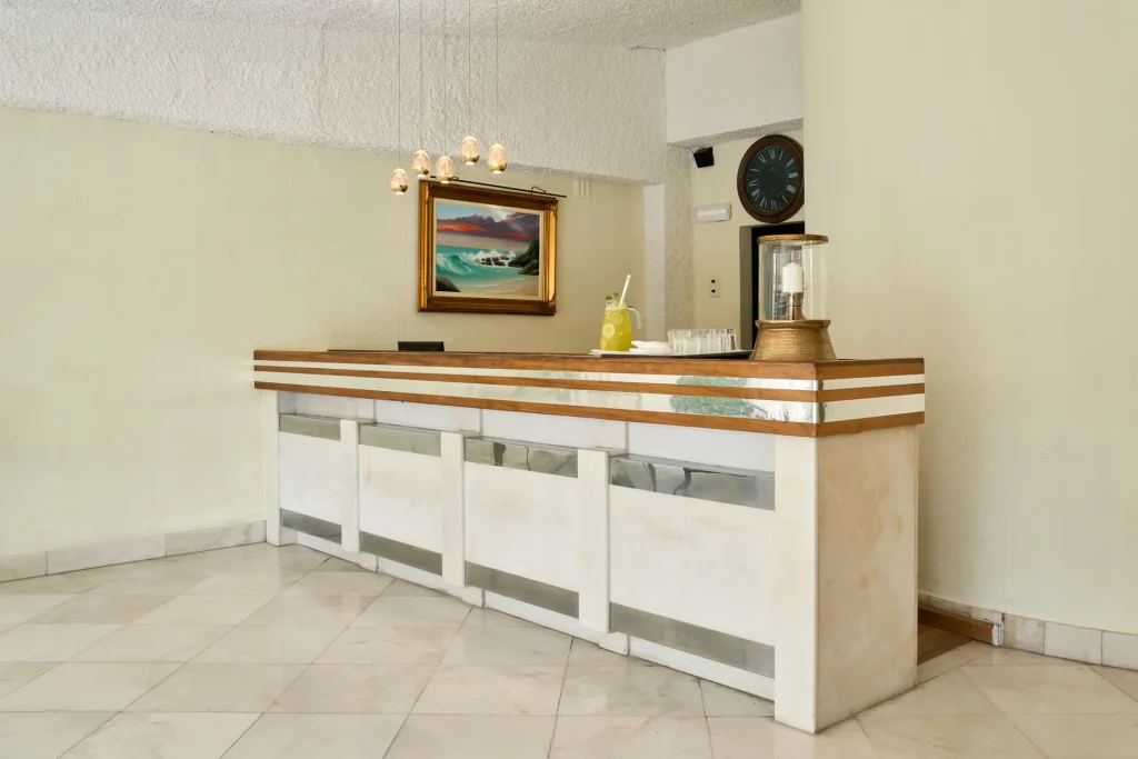 Modern reception desk with pendant lights, a landscape painting, and a clock in a minimalist setting.