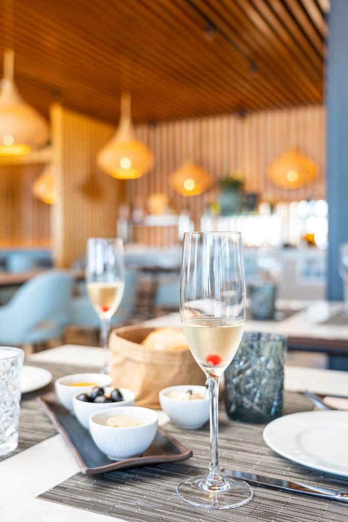 Champagne flute on a restaurant table, with small dishes of starters and elegant lighting.