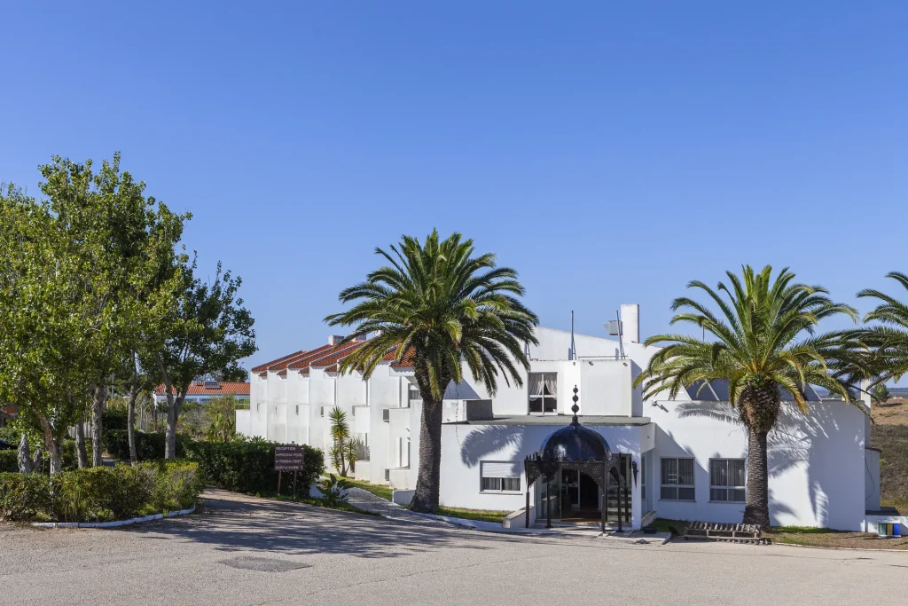 White building with palm trees under a clear blue sky and a decorative entrance.