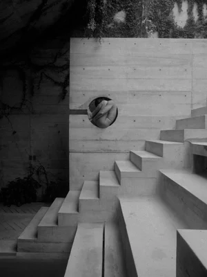 Grayscale concrete steps with a circular drain in front of a wall