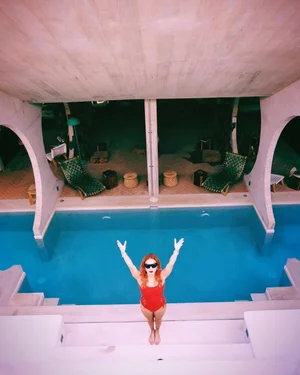 Woman posing in front of an outdoor pool with arched cabanas and lights