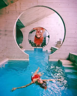 Person swimming underwater through a circular wall with a dog mural inside
