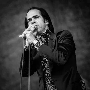 Black-and-white photo of a man singing into a microphone on stage