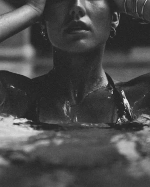 Black-and-white close-up of a woman with wet hands and dripping hair