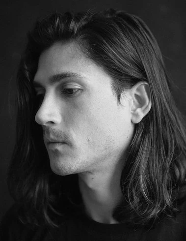 Black-and-white side profile of a man with shoulder-length dark hair