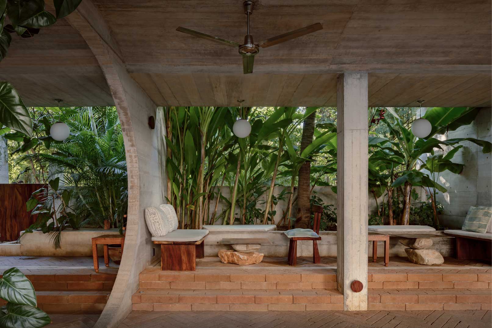 Tropical patio with ceiling fan, lounge seating, and large green plants