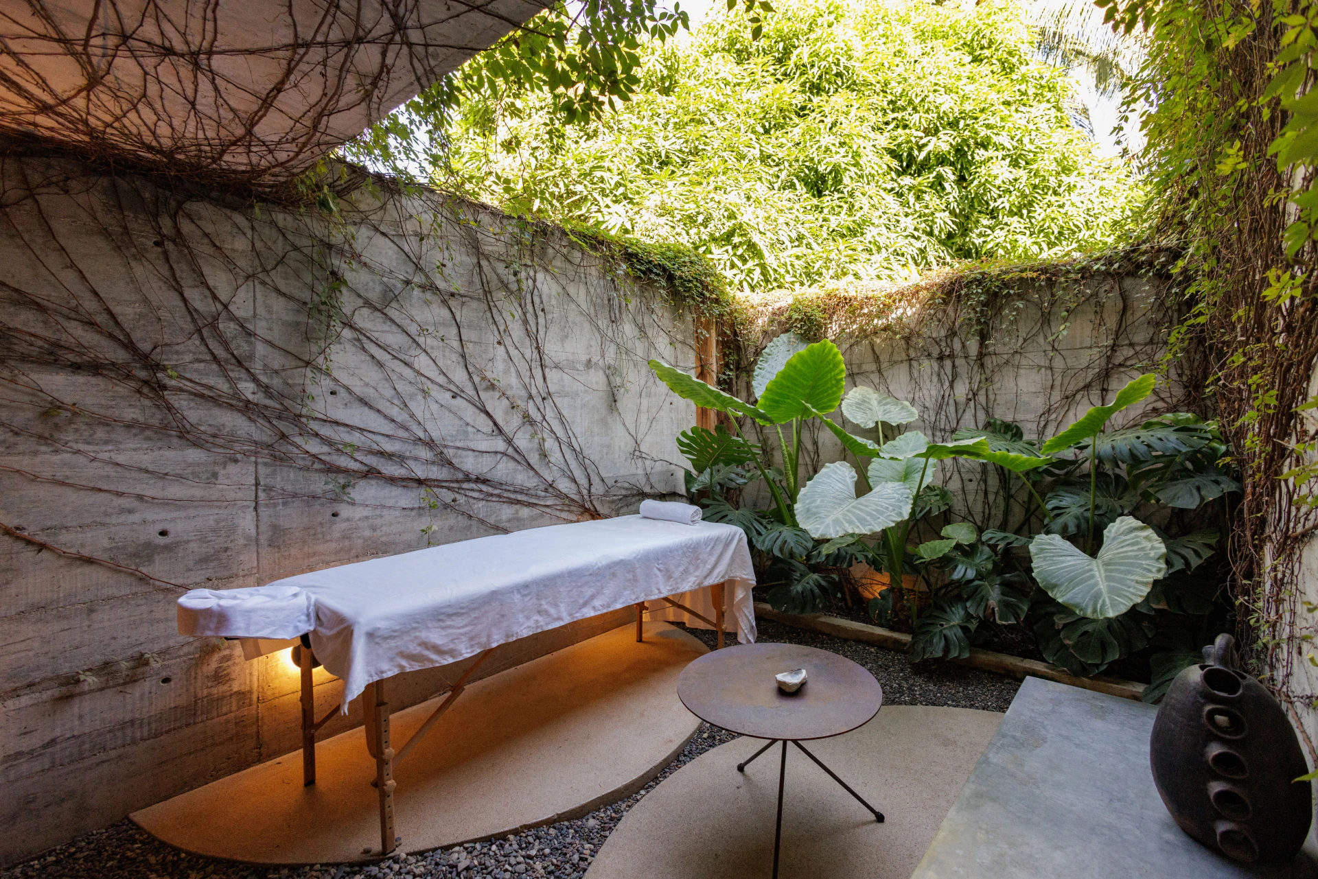 Massage table on a patio with tropical plants and sunlight through trees