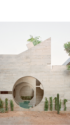Fachada de edificio de concreto con arco circular y plantas alrededor