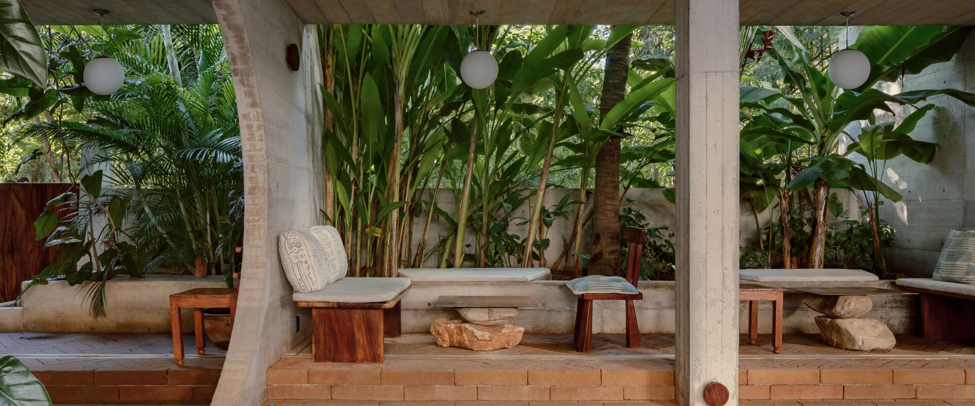 Outdoor patio with stone walls, wooden benches, and lush tropical plants