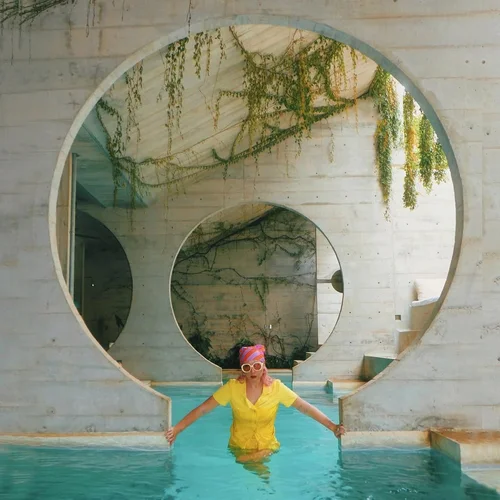 Child in yellow shirt plays in pool inside circular pool opening with vines