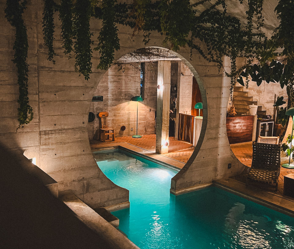 Piscina interior con pared de piedra y plantas colgantes, estilo vintage.