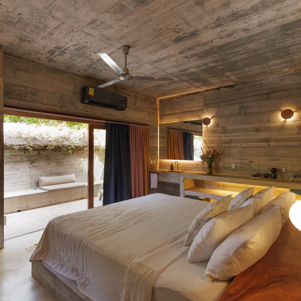 Dormitorio moderno con cama, ventilador de techo y ventanales al jardín