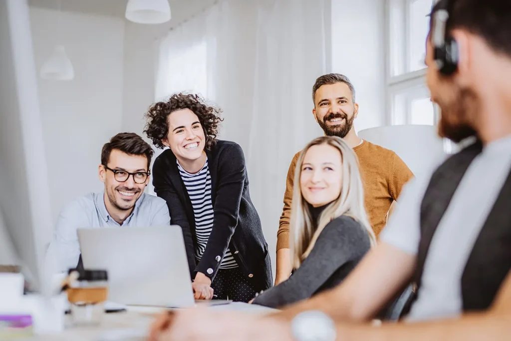 Grupo de personas sonrientes en una reunión de trabajo en una oficina luminosa.