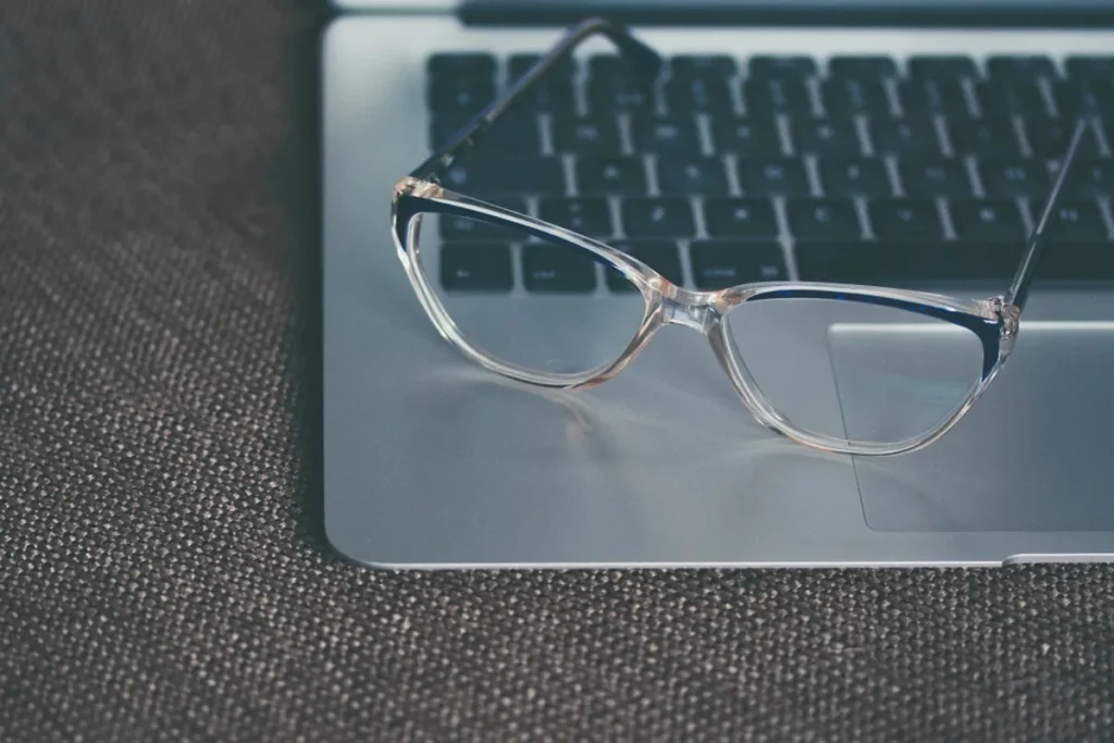Lentes transparentes sobre el teclado de una laptop, con fondo de tela gris.
