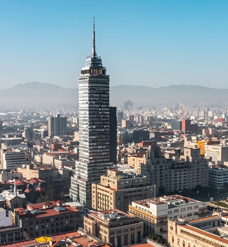 Vista de la Torre Latinoamericana en Ciudad de M&eacute;xico, con edificios y monta&ntilde;as al fondo.