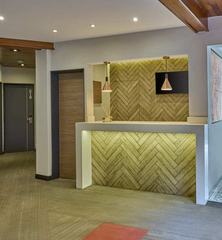 Recepci&oacute;n de hotel moderna con iluminaci&oacute;n c&aacute;lida y decoraci&oacute;n de madera en espiga.