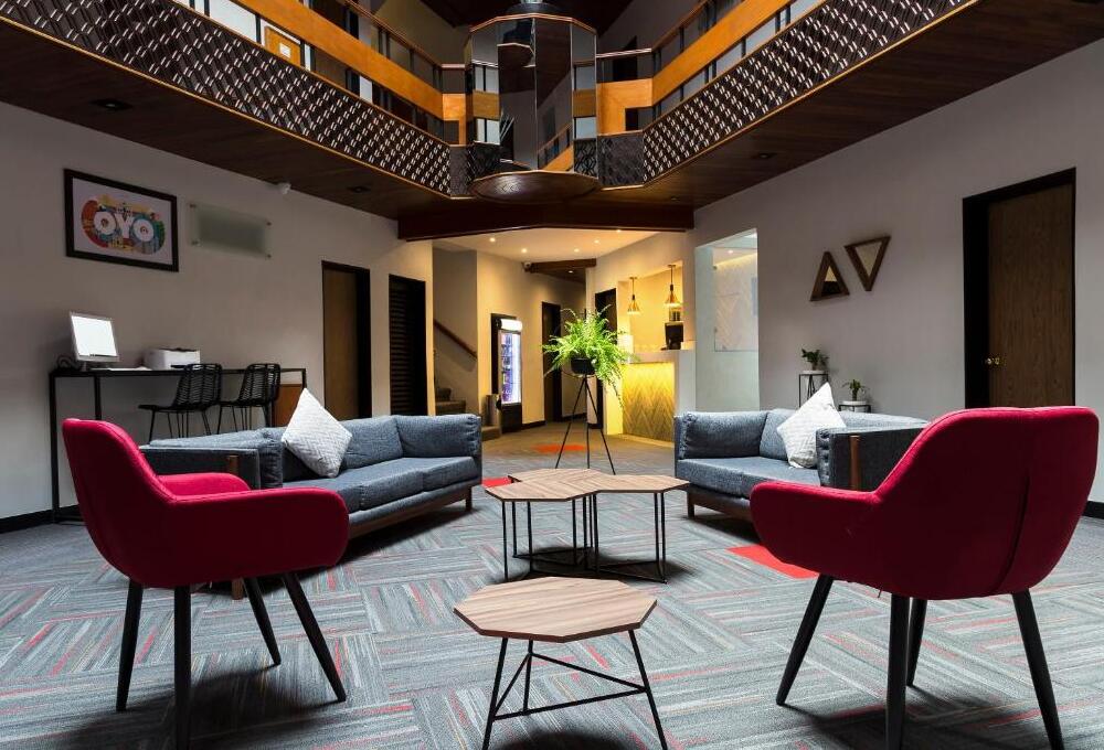 Sala moderna, con sillones grises y sillas rojas, mesas de centro de madera y decoraci&oacute;n elegante.