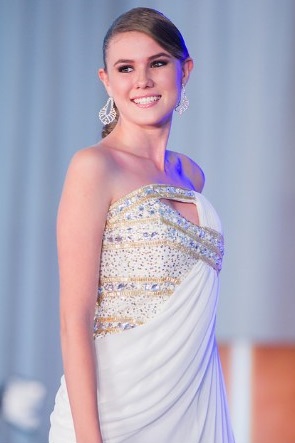 Persona sonriendo con un vestido blanco elegante y adornos brillantes sobre un fondo azul claro.