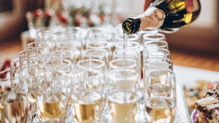 Botella de champán sirviendo varias copas en una celebración.