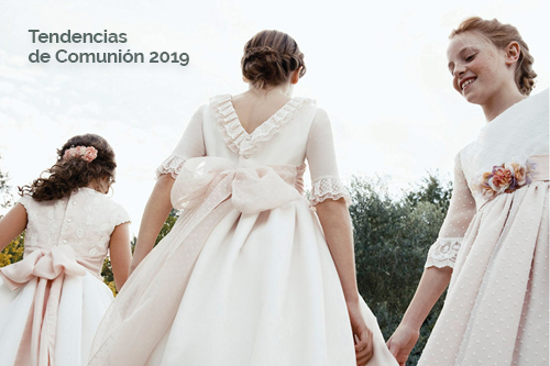 Niñas con vestidos de comunión blancos y rosados sonríen y caminan al aire libre, con texto "Tendencias de Comunión 2019".