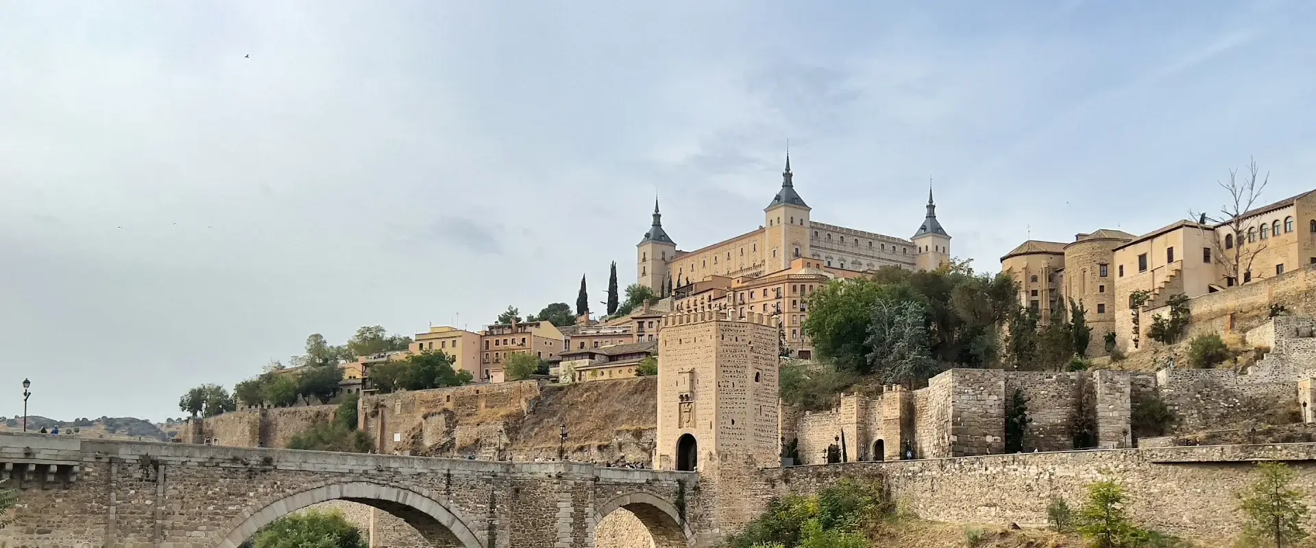 Vista panorámica de un castillo con torres y un puente de piedra en un entorno histórico.