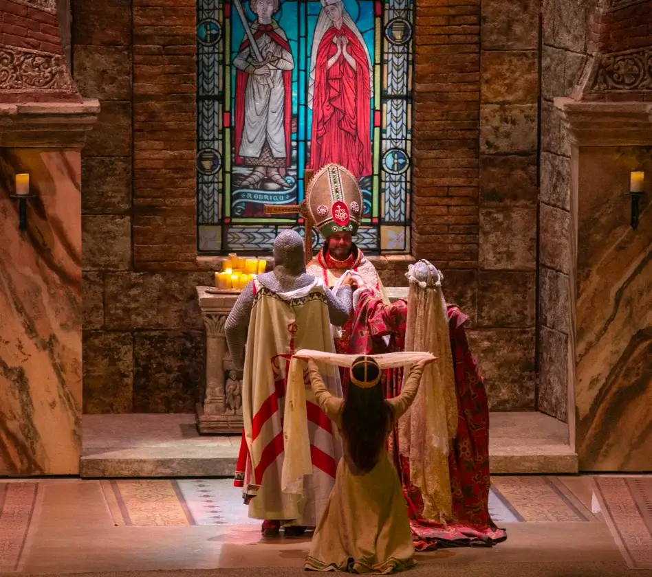 Una ceremonia medieval con un obispo, una pareja y un niño, frente a un vitral religioso en una iglesia.