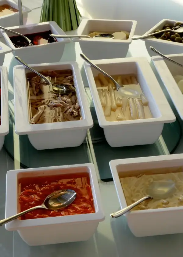 Cajas blancas con diferentes alimentos en gelatina, cada una con una cuchara de servir.