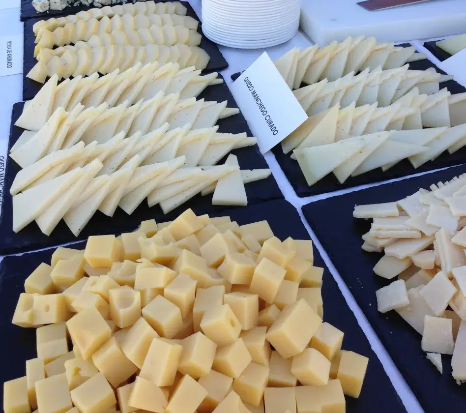 Variedad de quesos cortados sobre bandejas, con etiquetas indicando nombres.