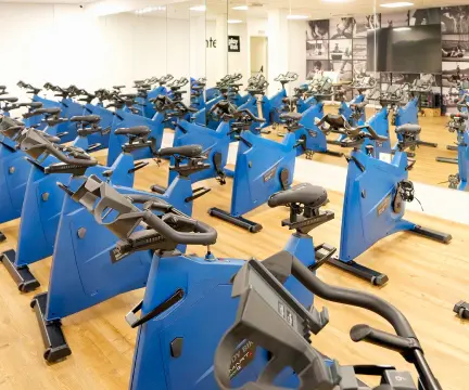 Estudio de spinning con numerosas bicicletas estáticas azules y espejos en las paredes.