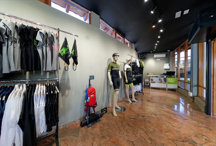 Tienda de ciclismo, con maniquíes y ropa deportiva en exhibición, configura un ambiente moderno y bien iluminado.