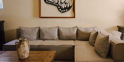 Sala de estar con sofá esquinero gris, mesa de madera y cuadro de ala de mariposa en la pared.
